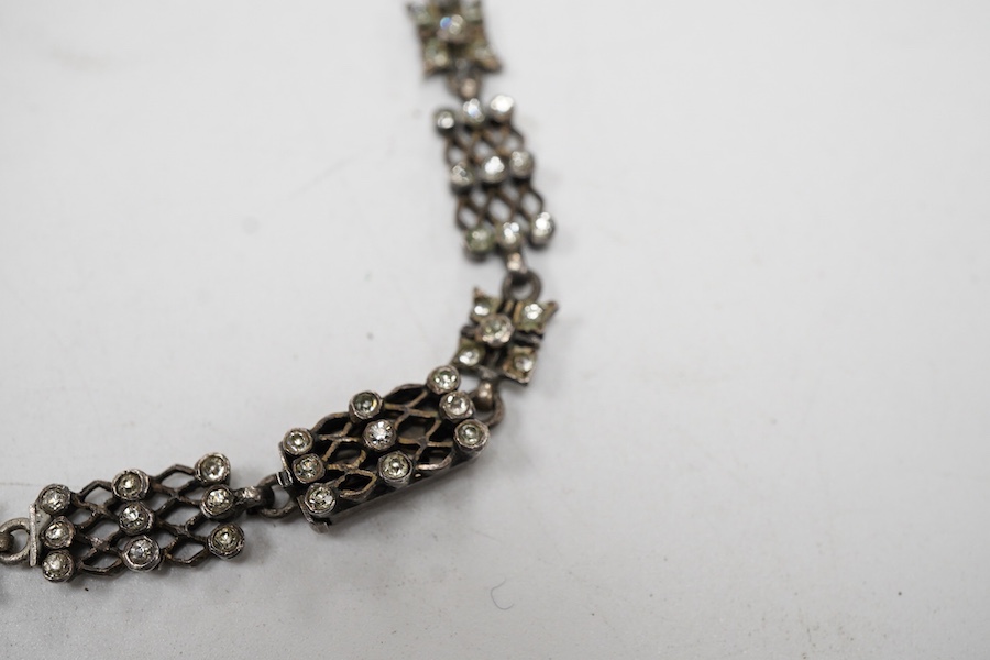 An early 20th century white metal and white paste set cluster necklace, each trellis style link mounted with nine paste stones, approx. 38cm.